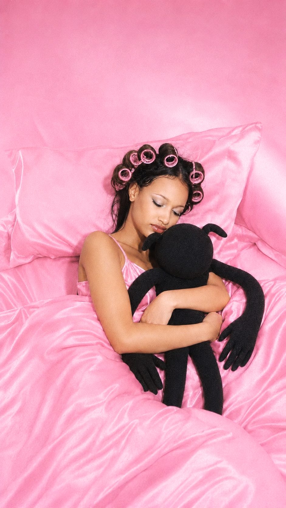 A woman in pink satin asleep, holding terry